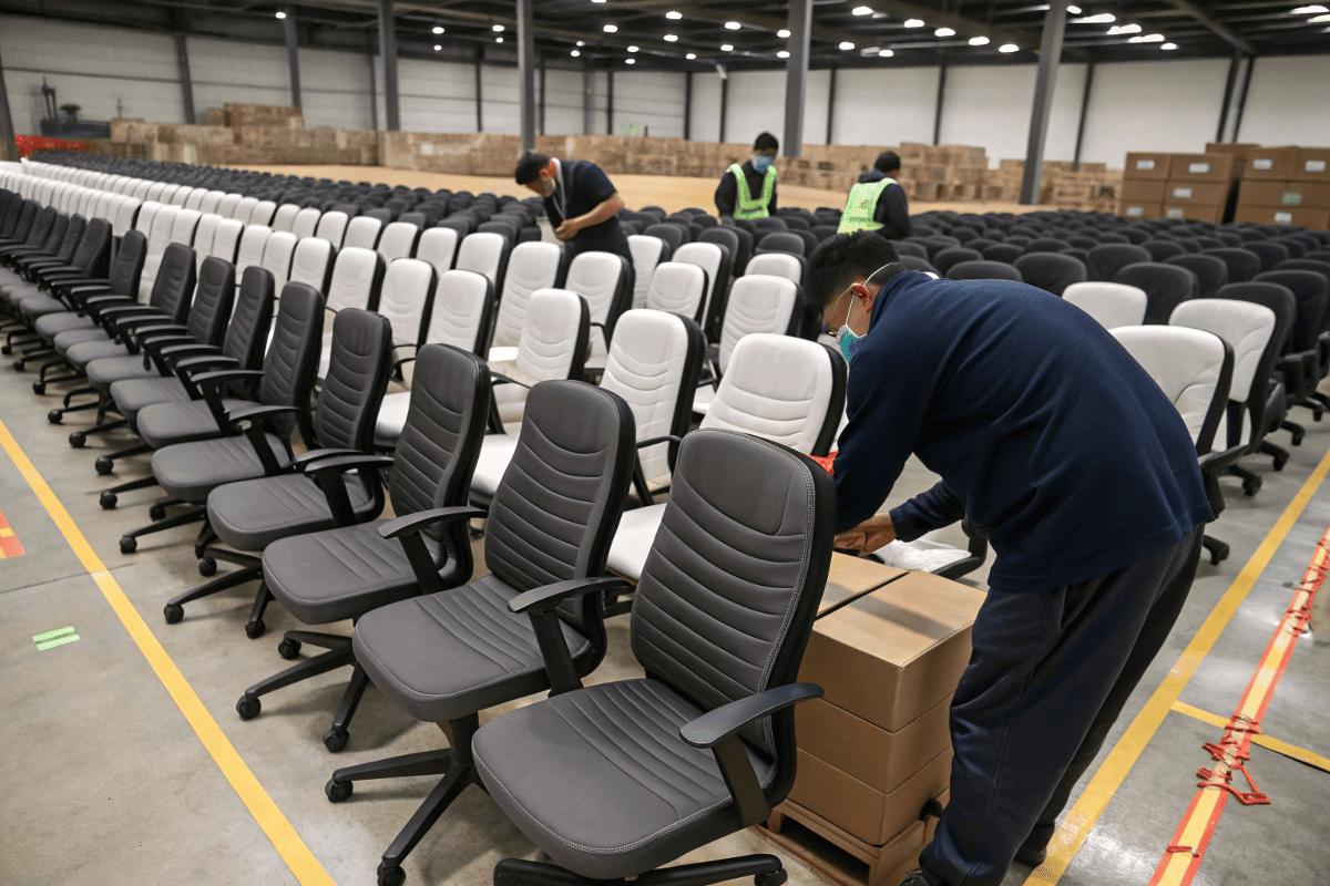 factory workers slicing large foam blocks into seat-sized layers